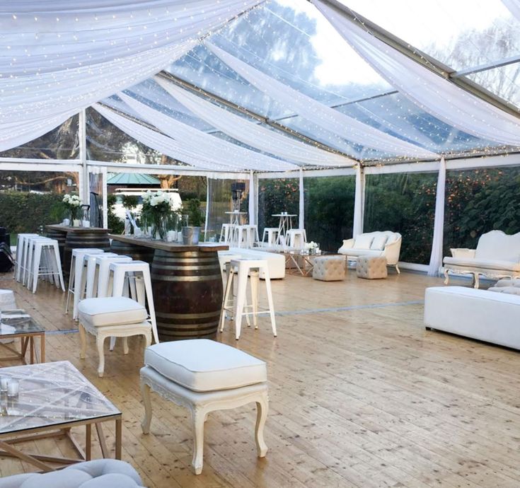 the inside of a tent with tables, chairs and couches on it's wooden floor