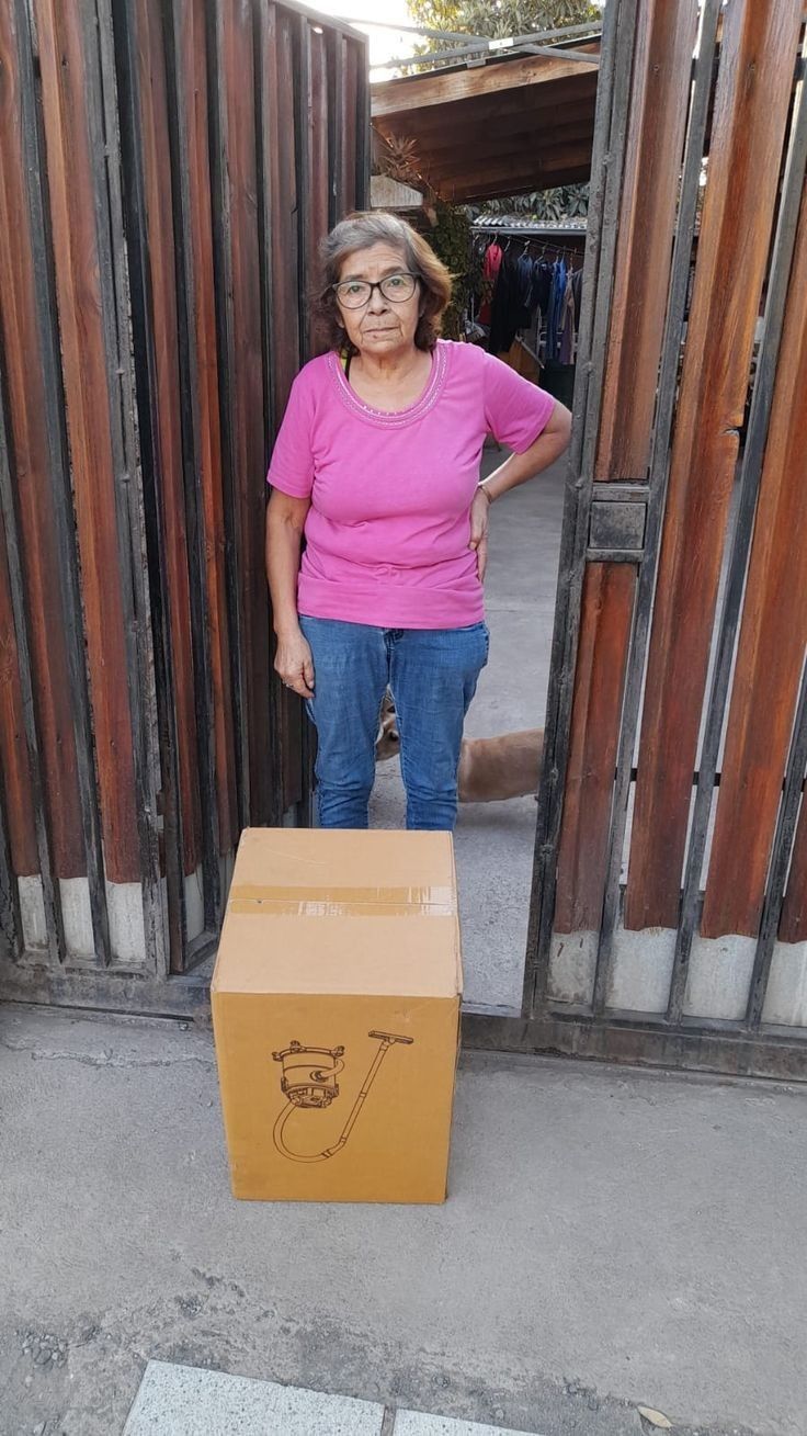 an older woman standing next to a cardboard box