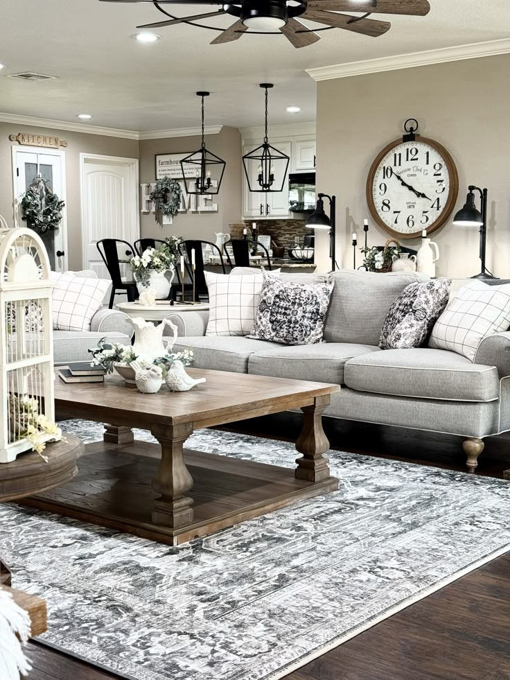 a living room filled with furniture and a large clock on the wall above it's windows