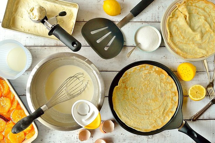 an overhead view of pancakes in pans with eggs, butter and other cooking utensils