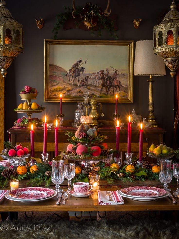 a dining room table set for christmas dinner with candles and fruit on the plates in front of it