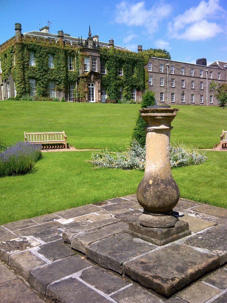 a large building sitting in the middle of a lush green field next to a park