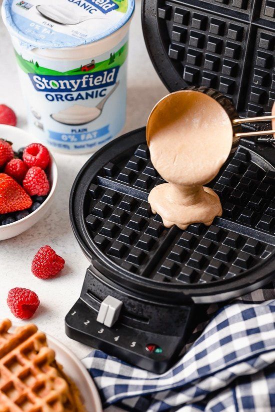 a waffle iron with strawberries and yogurt