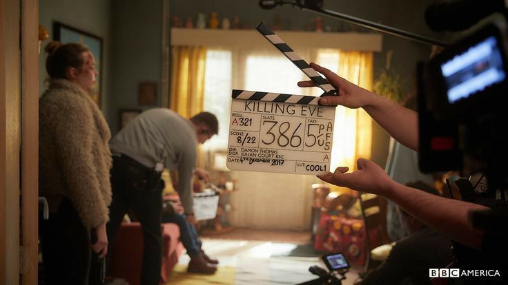 a person holding up a movie clapper in a room with other people standing around