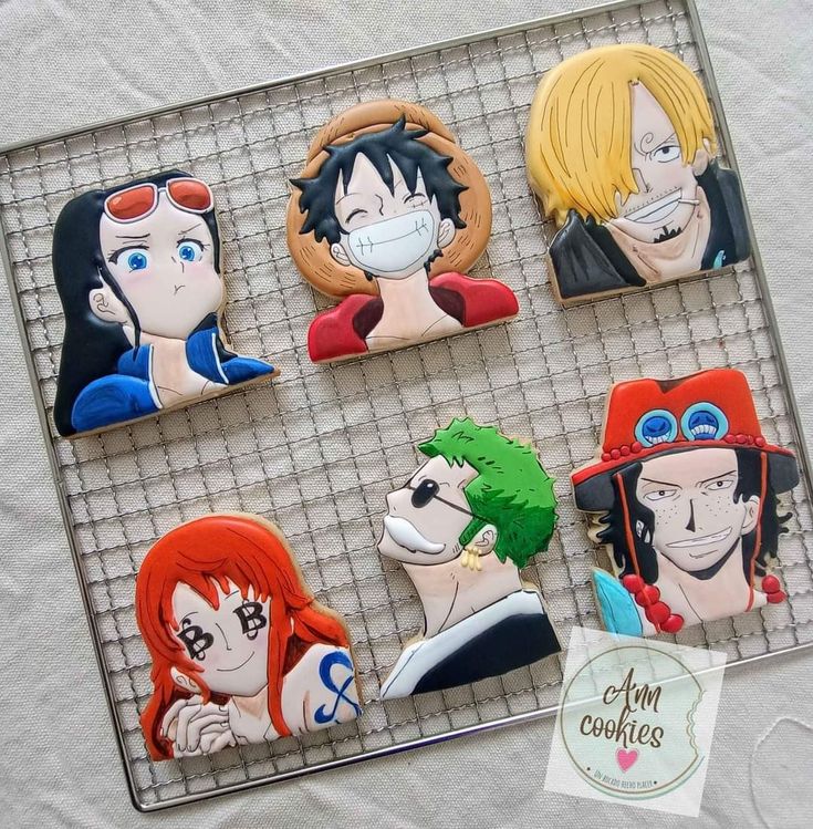 some anime character cookies are sitting on a tray with white paper and black wire behind them