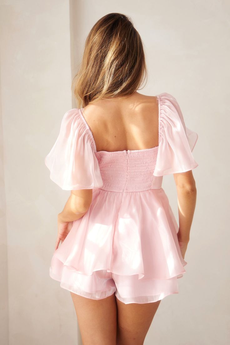 Introducing our Luxe Blush Flutter Sleeve Romper, designed to elevate your summer wardrobe effortlessly. This romper combines elegance with comfort, featuring: Flutter sleeves and a chic two-layered hem for a graceful silhouette. A smocked back and zipper closure for a secure and flattering fit. Crafted from 100% polyester, both self and lining, ensuring a luxurious feel. Perfect for any occasion. Ideal for summer outings, parties, and casual gatherings, the Luxe Blush Flutter Sleeve Romper embo Chic Summer Mini Jumpsuits And Rompers, Chic Summer Jumpsuits And Rompers Mini Length, Summer Jumpsuits And Rompers With Ruffles For Day Out, Spring Jumpsuits And Rompers With Smocked Bodice For Brunch, Spring Brunch Jumpsuits And Rompers With Smocked Bodice, Summer Brunch Jumpsuit With Ruffles, Flirty Ruffled Jumpsuits And Rompers For Summer, Elegant Pink Jumpsuits And Rompers For Summer, Elegant Summer Peplum Top