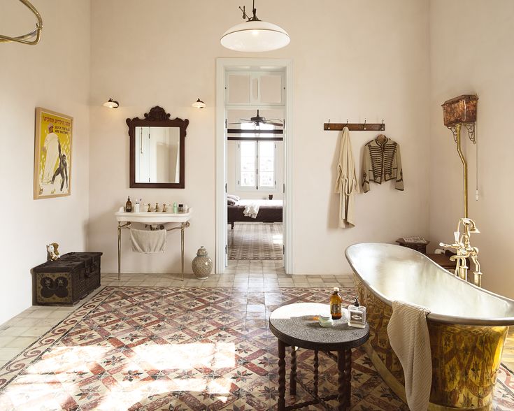 a bath room with a tub a sink and a mirror on the wall next to a table