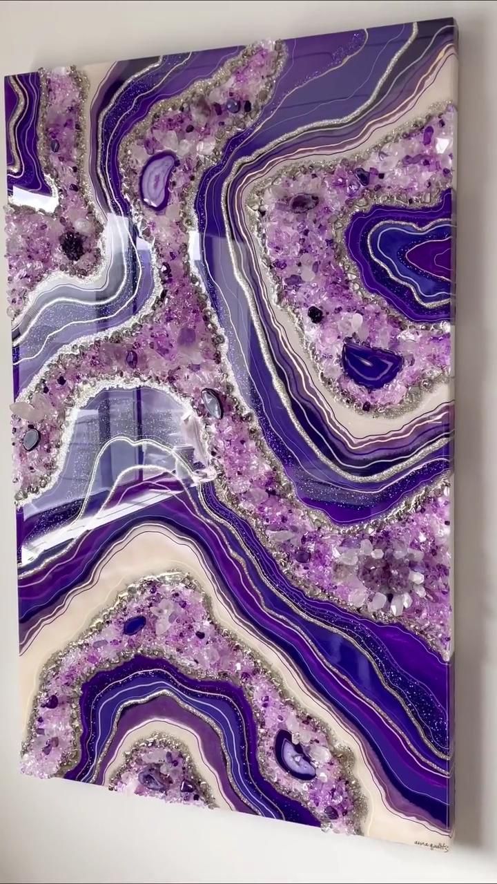 a purple and white abstract painting hanging on a wall