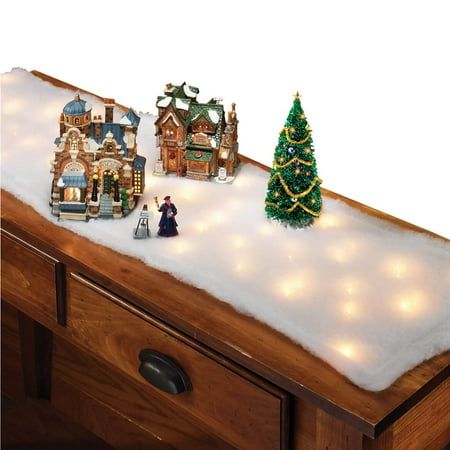 a small christmas tree on top of a wooden dresser with lights and decorations around it