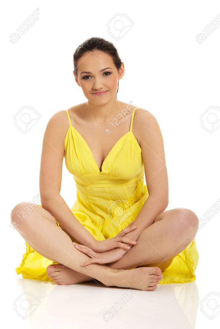 a beautiful woman in yellow sitting on the floor with her legs crossed and smiling at the camera