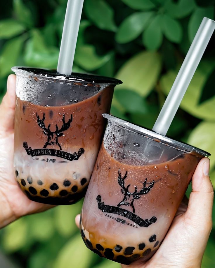 two people holding up glasses with drinks in them, one is brown and the other is black