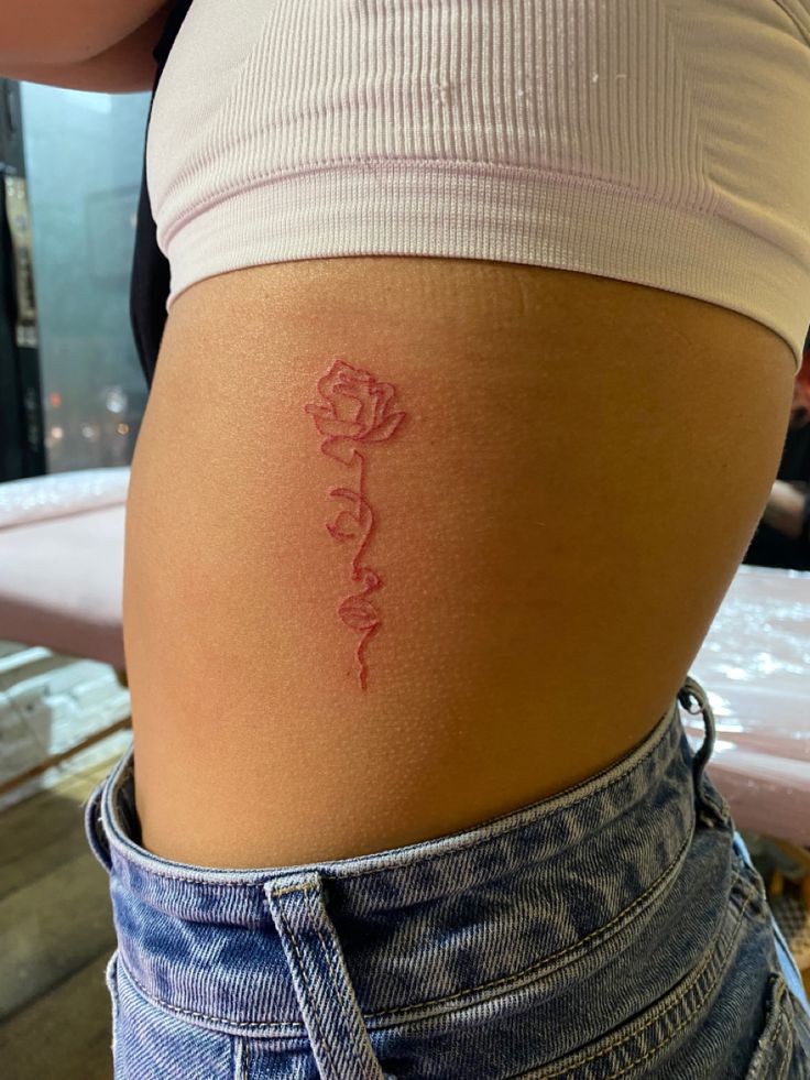 a woman's stomach with a rose tattoo on her lower back and the word love written in cursive writing