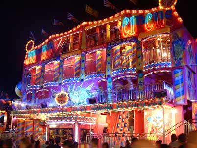 an illuminated building with lots of lights on it's sides and people walking around