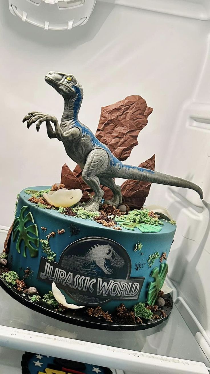 a dinosaur cake sitting on top of a refrigerator