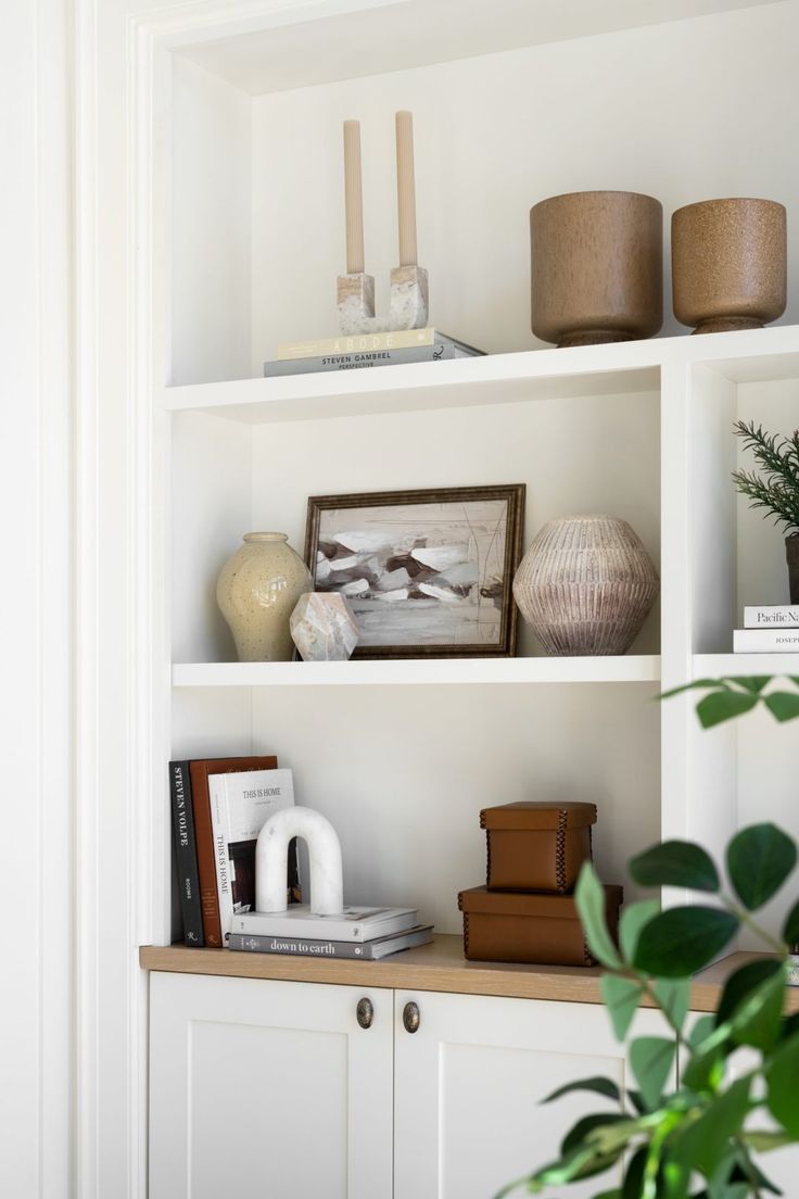 some white shelves with plants and pictures on them