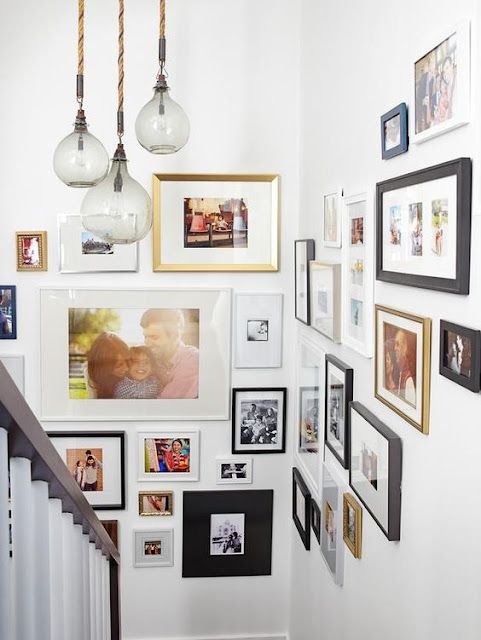 a staircase with many pictures on the wall and framed photos hanging up against the wall