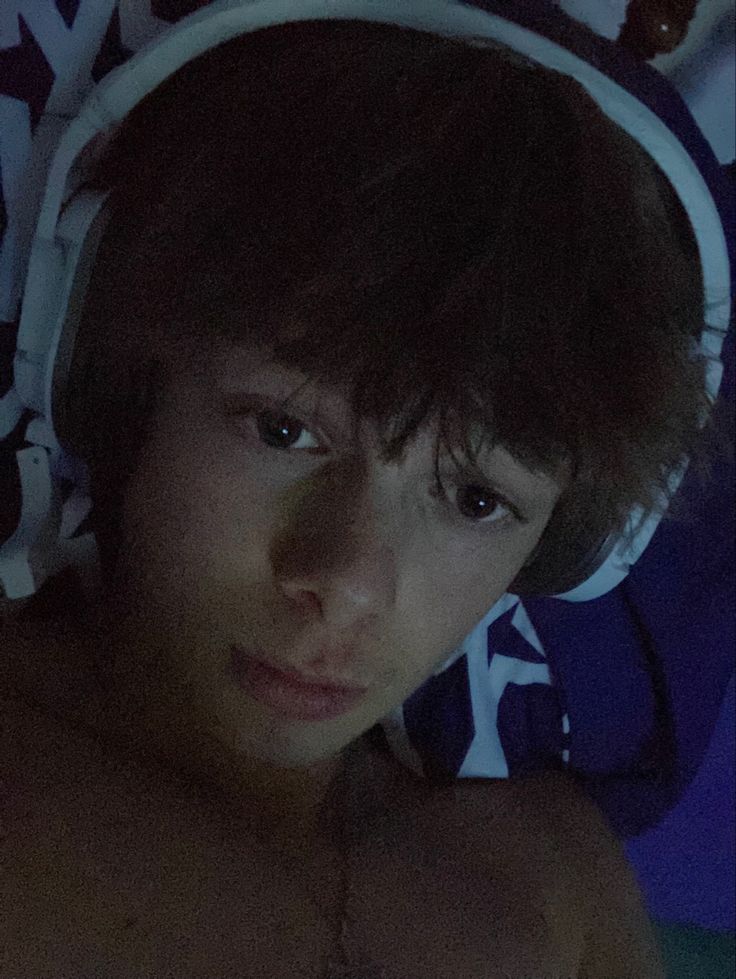 a shirtless young man wearing headphones in the dark