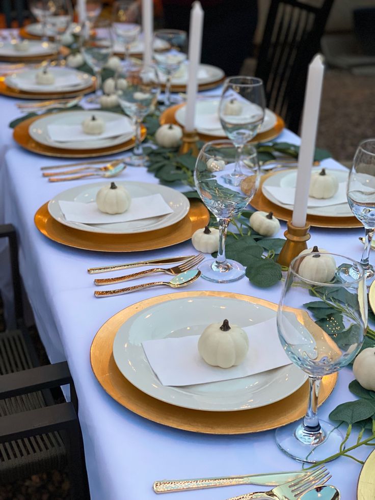 the table is set with white pumpkins and greenery for an elegant thanksgiving dinner