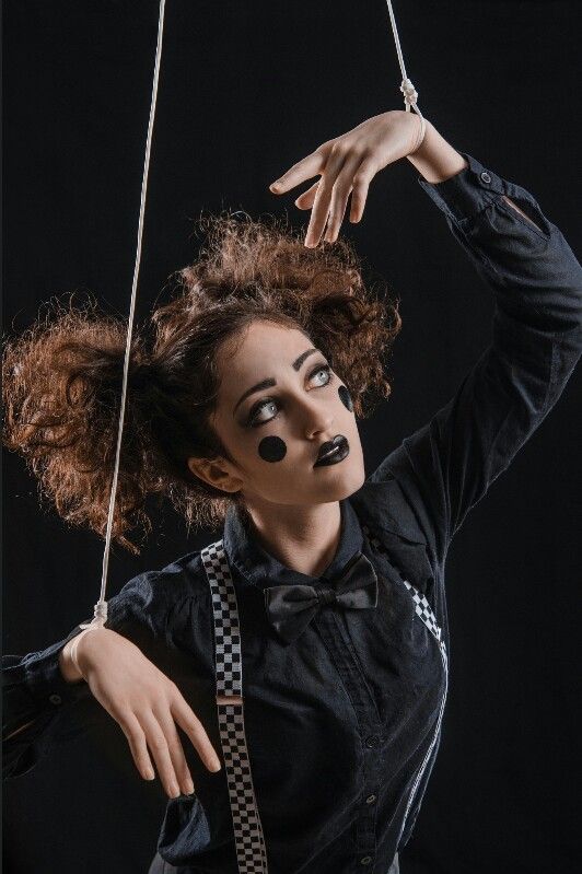 a woman in black shirt and tie with fake makeup on her face holding onto a string