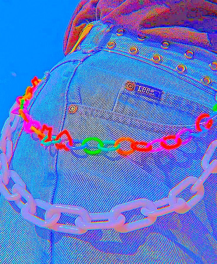 a person with a chain around their waist and wearing a jean jacket that has rainbow colored chains on it