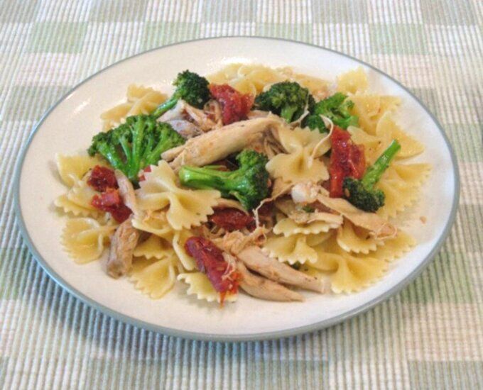 a white plate topped with pasta and broccoli on top of a checkered table cloth