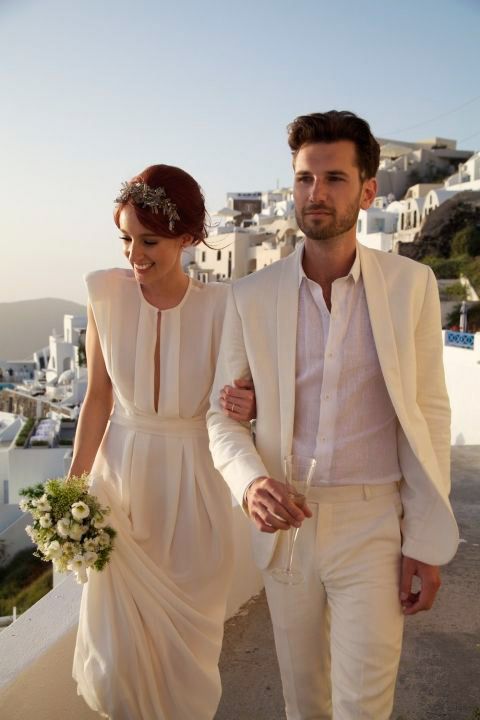 a man and woman are walking down the street together, dressed in all white attire