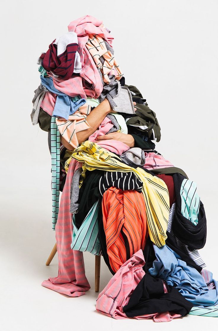 a pile of clothes sitting on top of a wooden chair next to a white wall