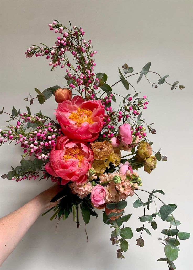 a bouquet of flowers is being held up by someone's hand on a white background