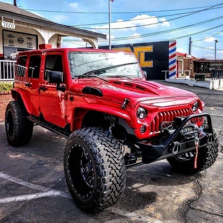 a red jeep parked in front of a gas station