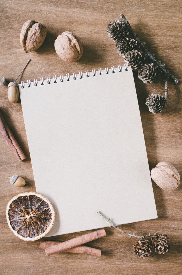 an open notepad sitting on top of a wooden table next to dried fruit and nuts