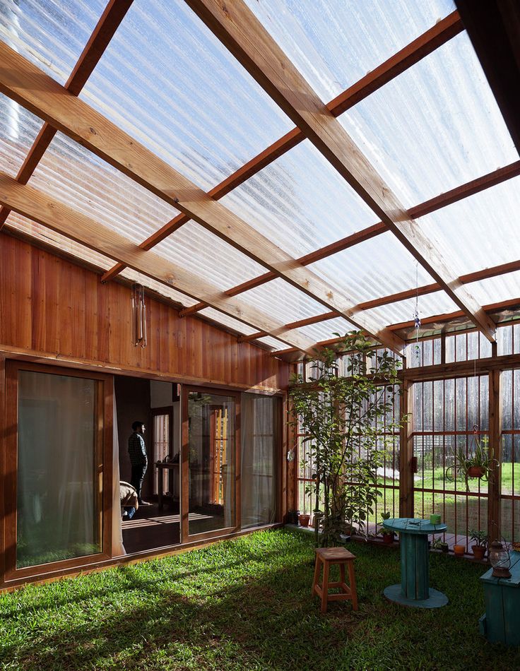 the inside of a house with lots of windows and grass on the ground in front of it