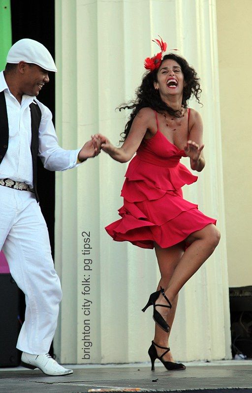 a woman in a red dress dancing with a man