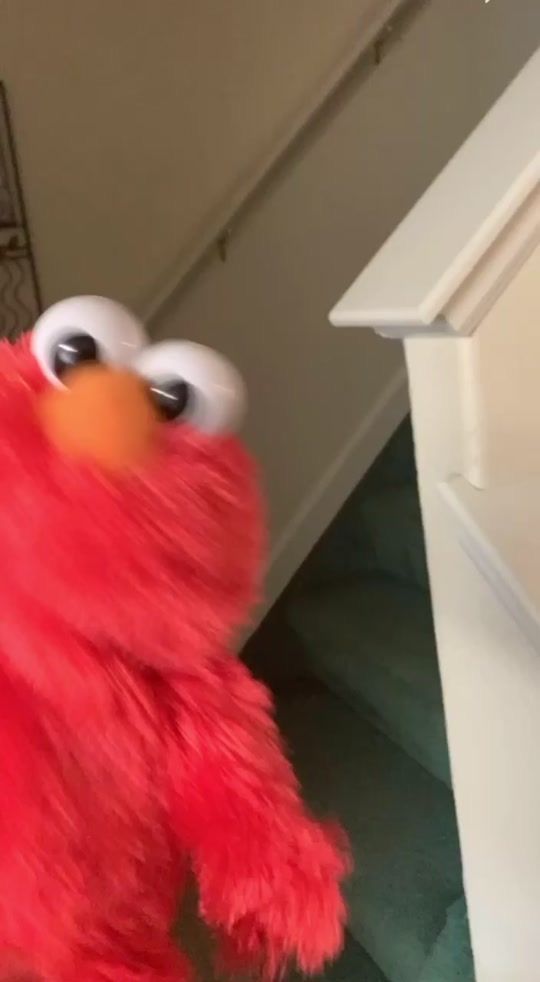 a red stuffed animal with big eyes standing next to stairs