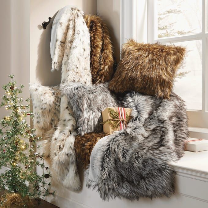 a window sill filled with lots of furry pillows and blankets next to a christmas tree