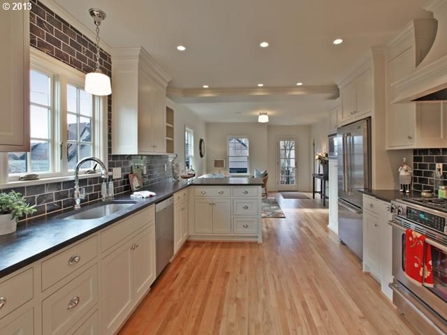 a large kitchen with white cabinets and wood flooring is seen in this image from the inside