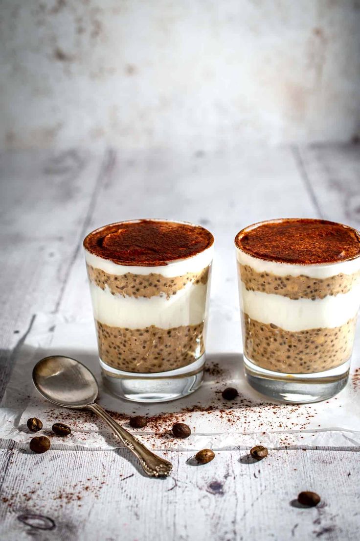 two glasses filled with dessert sitting on top of a table