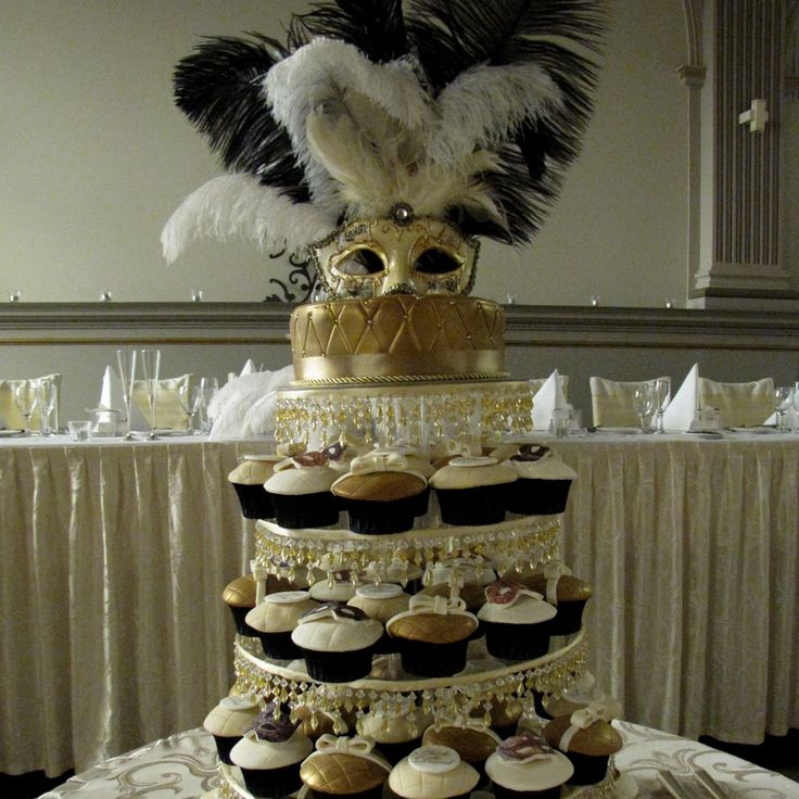 a three tiered cake with cupcakes and feathers on the top is decorated in black, white and gold