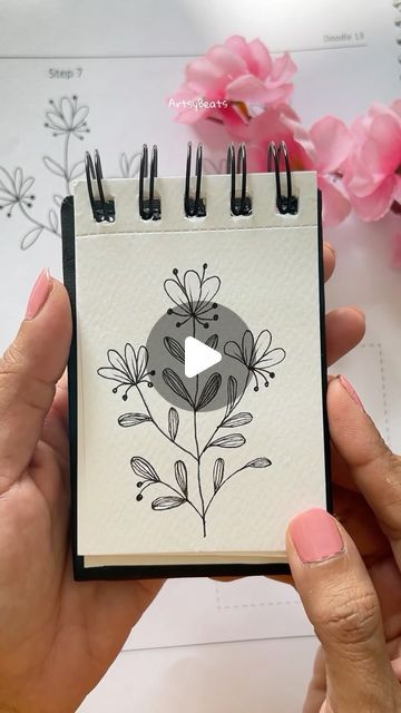 a hand holding a small notebook with flowers on it