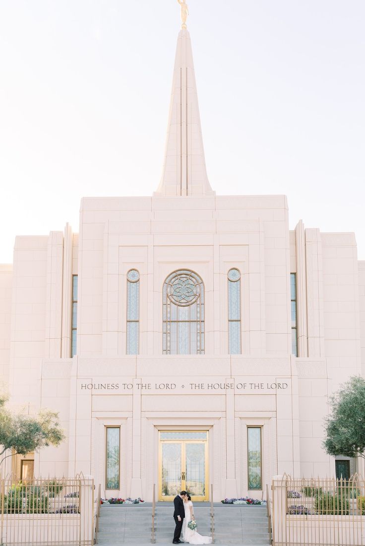 a bride and groom standing in front of the mormon temple during their wedding photo session