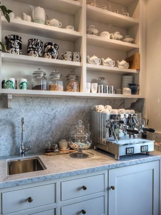 a kitchen with white cabinets and shelves filled with cups, saucers, and other items