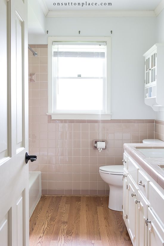 a bathroom with pink tile and wooden floors