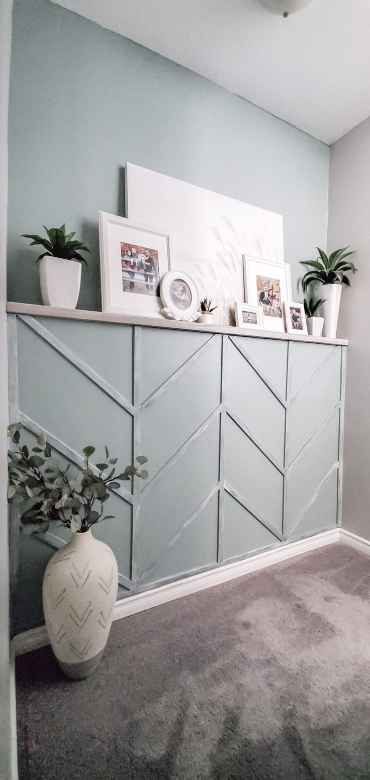 a white vase sitting on top of a wooden shelf next to a wall filled with pictures