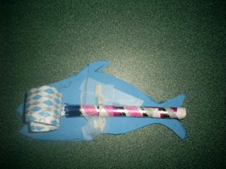 a toothbrush laying on top of a blue fish shaped object with pink and white stripes