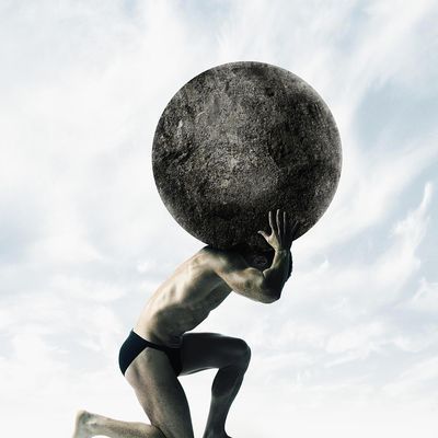 a man carrying a large rock over his head on top of the ground in front of a blue sky