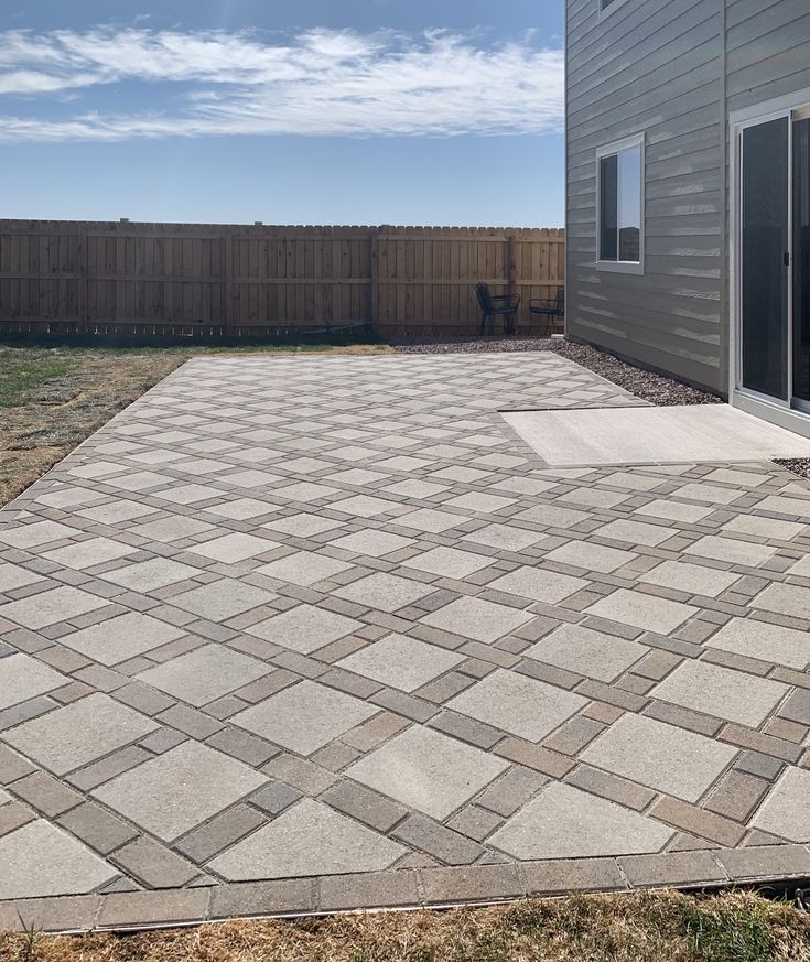 an empty backyard with a brick paver patio and sliding glass door to the back yard