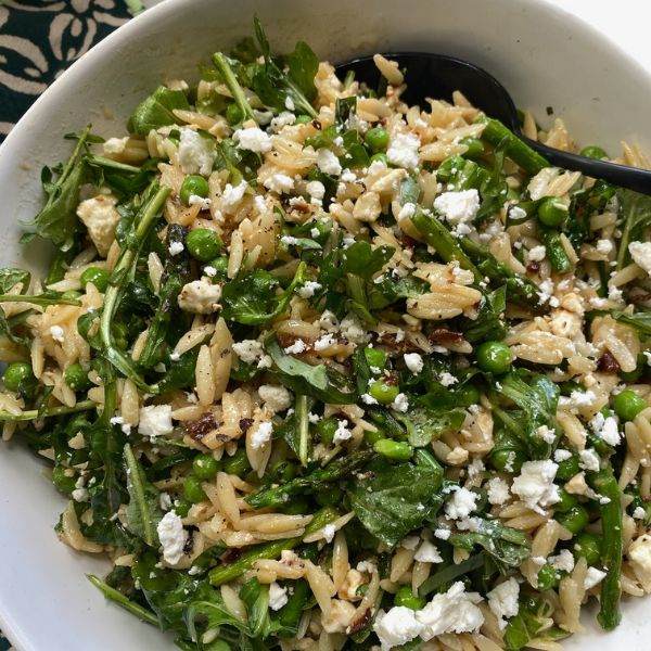 a white bowl filled with pasta and greens