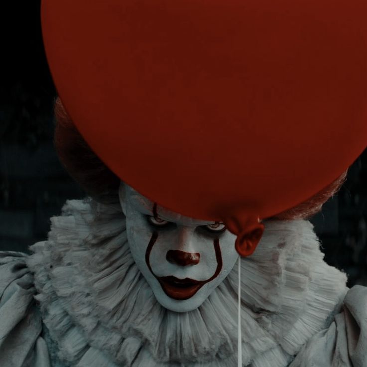 a clown with a red balloon on his head