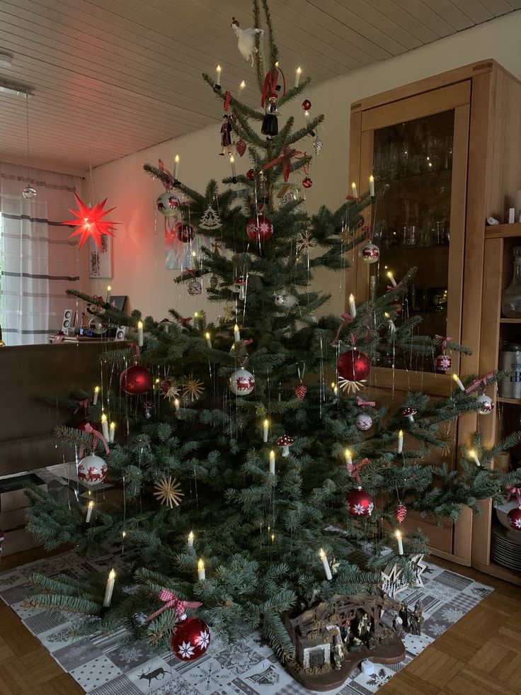 a christmas tree with ornaments on it in a living room