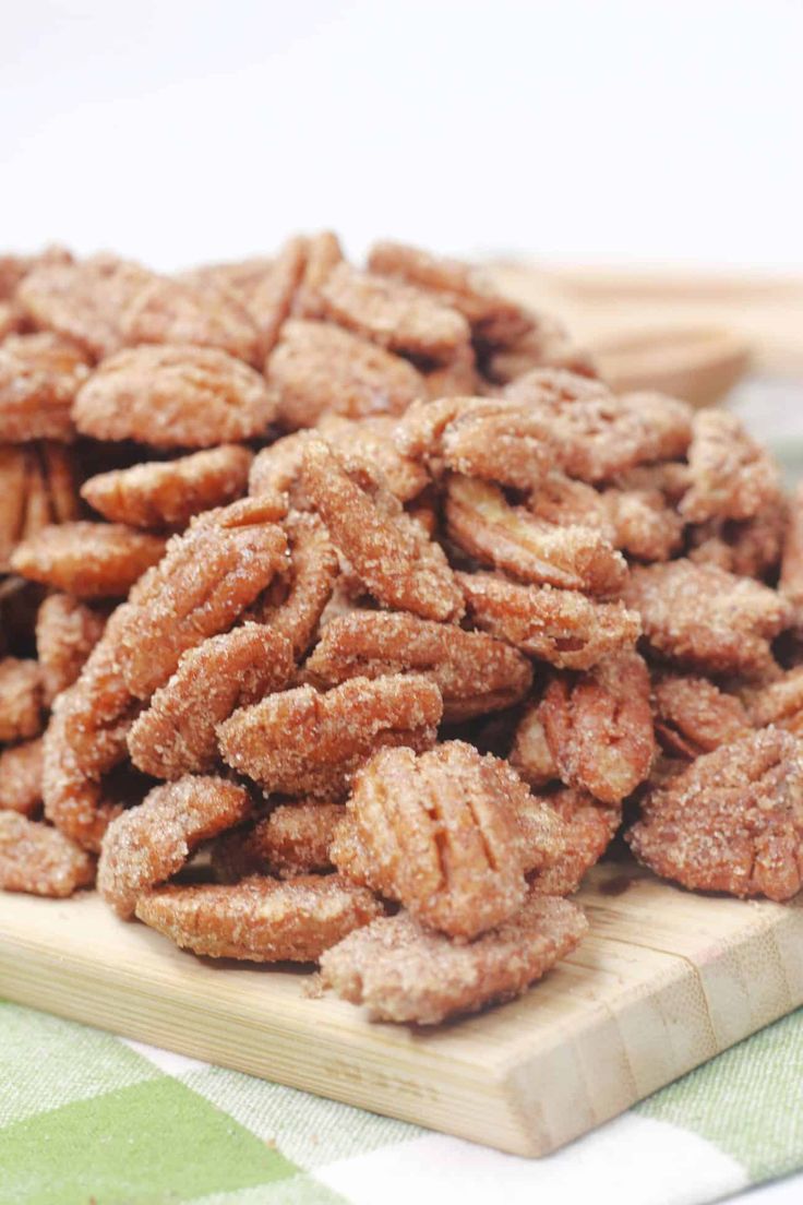 a pile of sugared pecans sitting on top of a cutting board next to spoons