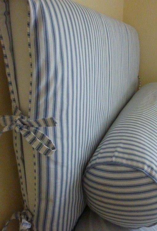 a blue and white striped pillow sitting on top of a bed next to a wall